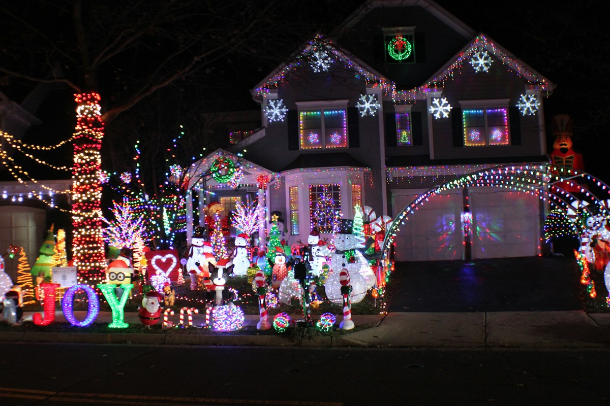 A real home with colorful Christmas roofline lights and illuminated yard decorations