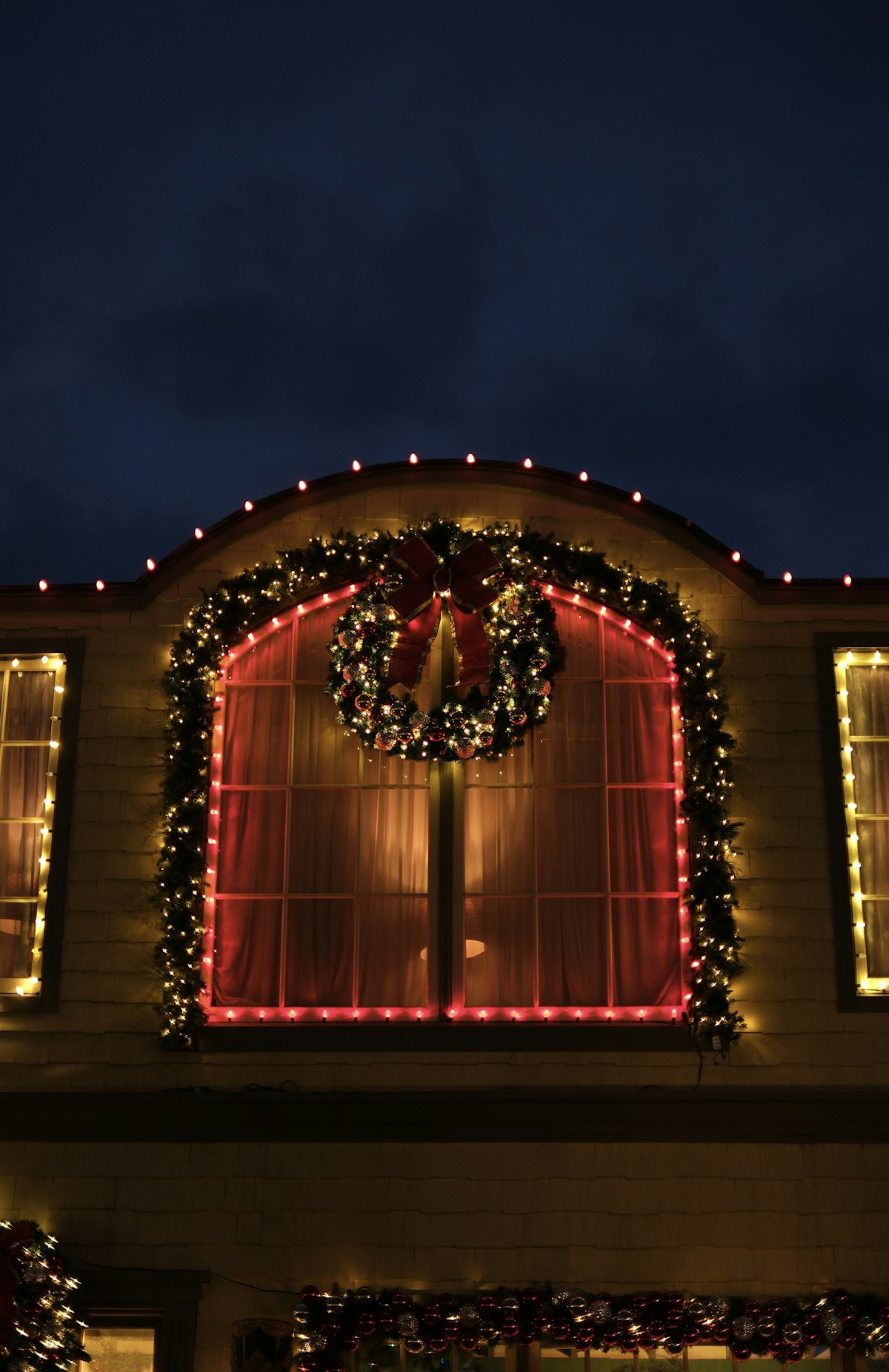 Wreaths, garlands and red Christmas lights decorating a home exterior